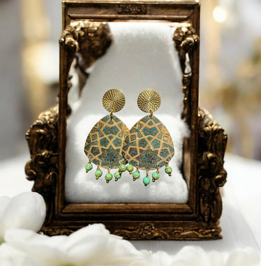 Gold and green earrings on a decorative stand with a soft focus background Mehrartcollections