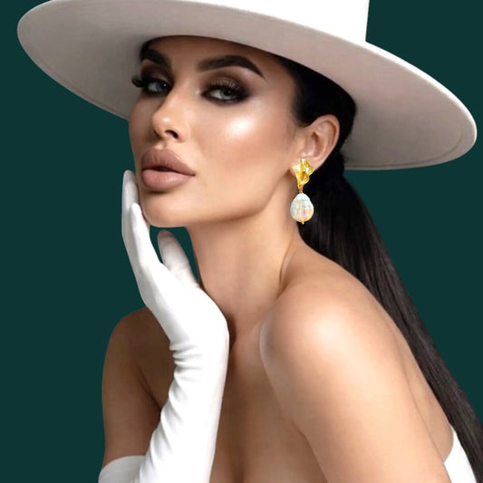 Woman wearing a white hat, white gloves, and pearl earrings against a green background